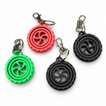 3D printed wheel spinner keyrings in black, red and green with metal rings and clips on a white background